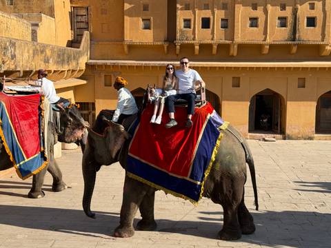 Two people riding an elephant with a guide.