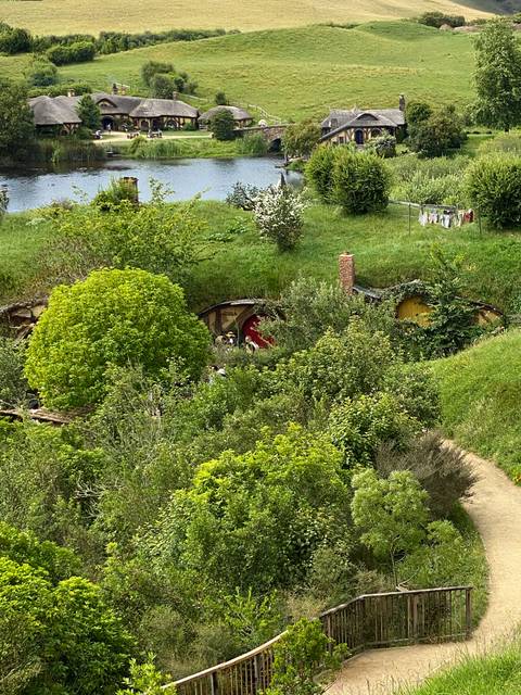       Hobbit-like house built into a hill surrounded by lush greenery.
  