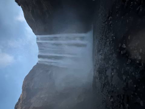 Tall waterfall cascading down a mountain with mist.