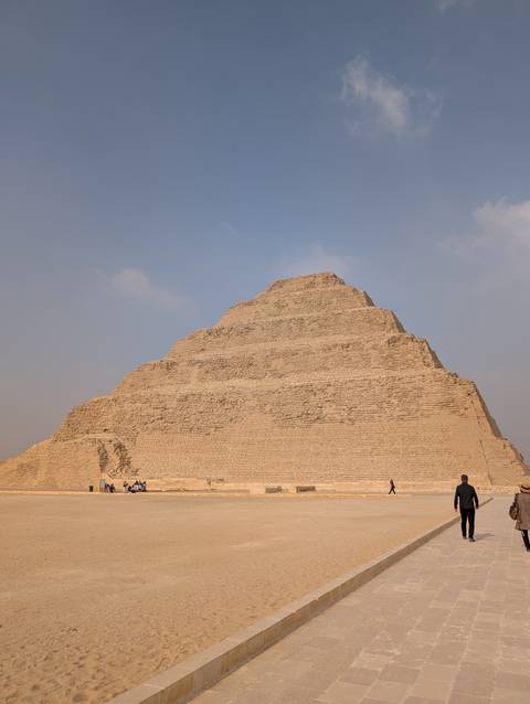       The Step Pyramid of Djoser at Saqqara with people in the foreground.
  