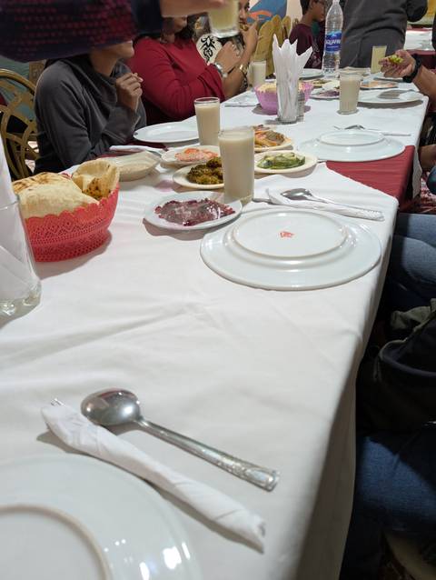 Empty dining table with plates and basket of bread.