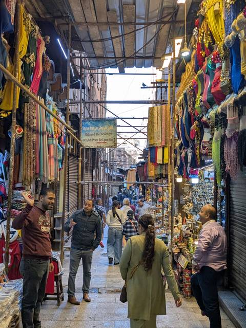 Busy market street with colorful textiles and people.