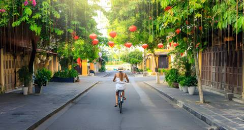 Person cycling on a street decorated with lanterns