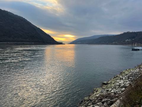 Serene view of a river at sunset with mountains in the background.