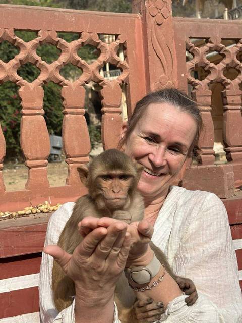       Smiling woman holding a young monkey.
  