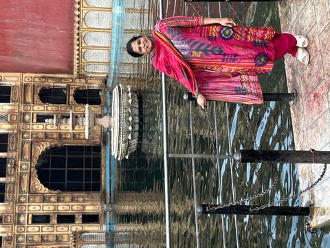       Woman standing near a railing in front of a fountain.
  