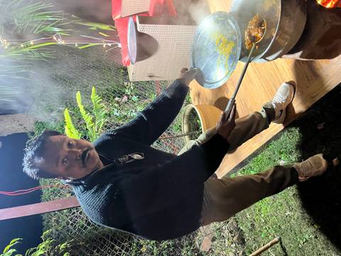       Man cooking food on an outdoor stove at night.
  