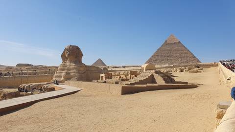 The Sphinx and Pyramids of Giza under a clear blue sky in Egypt.
