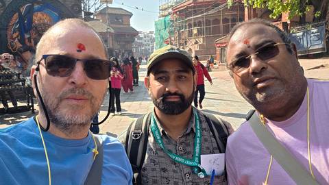       Three men taking a selfie with a temple in the background.
  
