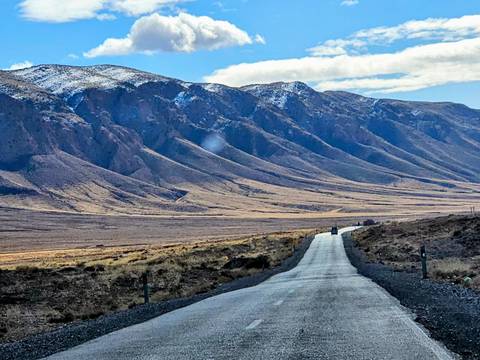 A desert road leading towards rugged mountains.