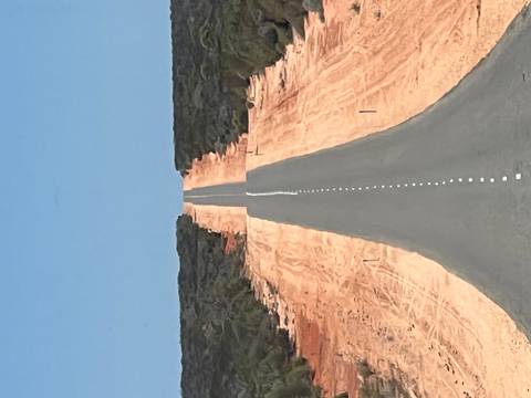 Straight road disappearing into the horizon through arid land.