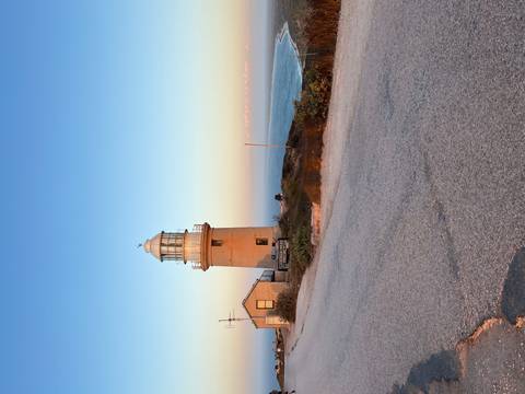 Lighthouse on a coastal cliff during sunset.