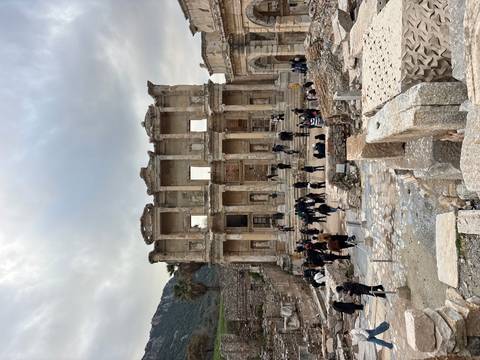 Ruins with people in the foreground, under cloudy sky.