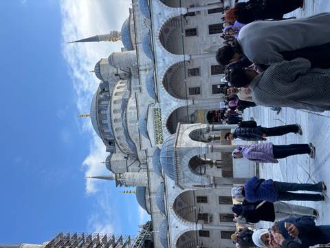 People outside a large, historic mosque with minarets.
