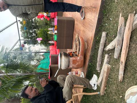 Cooking pot on an outdoor fire with people gathered around.