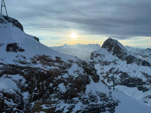 Snowy mountain landscape at sunset with a clear sky.