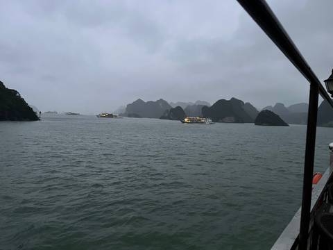 Boats on a foggy river with rugged limestone formations.