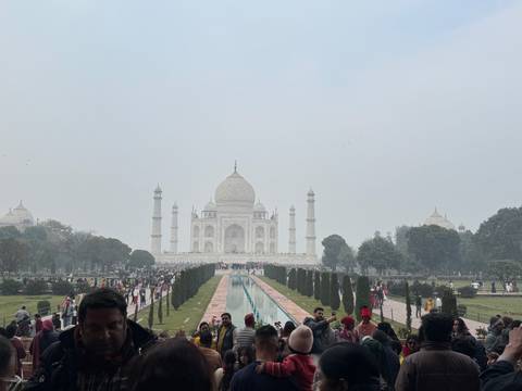       Tourist area with the Taj Mahal in the distance and many visitors.
  