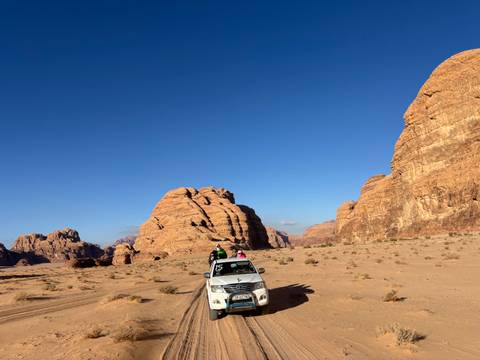      Two people standing on a vehicle exploring the desert landscape.
  