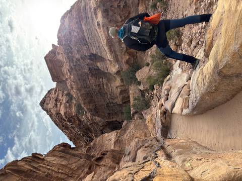       Tourist hiking in a rocky canyon with dramatic rock formations.
  