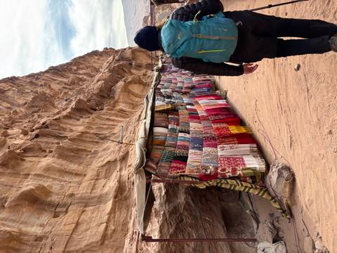       Marketplace stands set up in a rocky canyon selling colorful textiles.
  