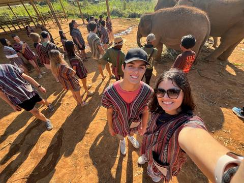 Selfie of a couple with elephants in the background.