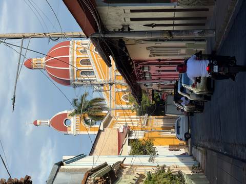       Colorful colonial buildings with people and vehicles on a street.
  