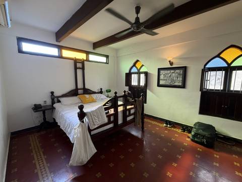       A cozy bedroom with a wooden bed and stained glass windows.
  
