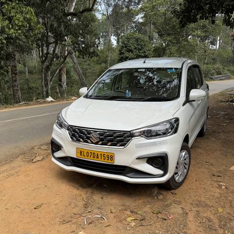       White car parked on a roadside with trees.
  