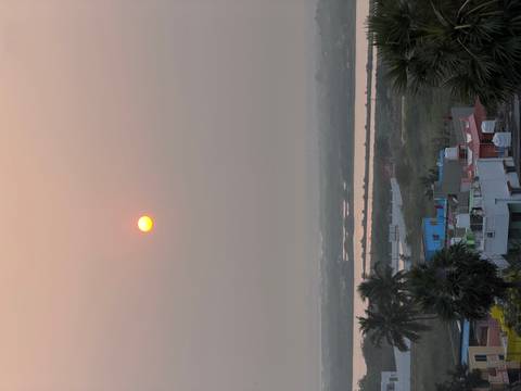       Distant sunset view over a landscape with buildings and palm trees.
  