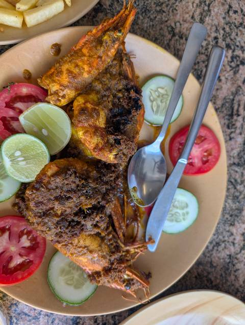       A plate of roasted prawns with various garnishes.
  