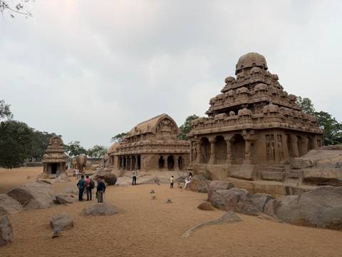      Group of historical stone temples with people exploring.
  