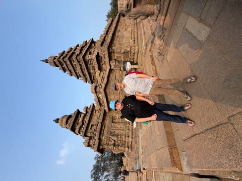 Two men posing in front of an ancient temple.