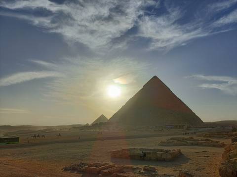       Pyramids in Giza with the sun setting in the background.
  