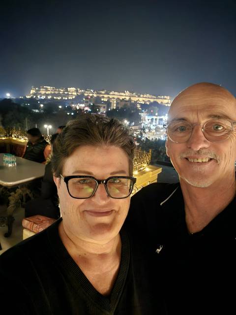       Close-up of two people indoors with city lights in the background.
  