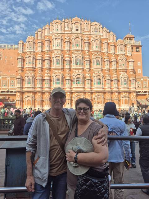       Couple posing in front of the iconic pink Hawa Mahal, with a bustling crowd.
  