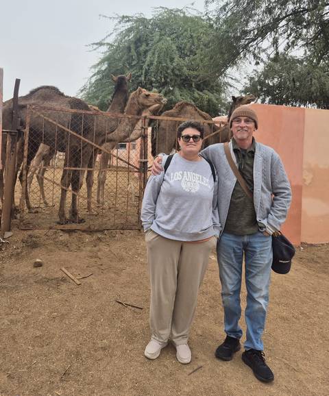       Couple posing in front of a camel stable.
  