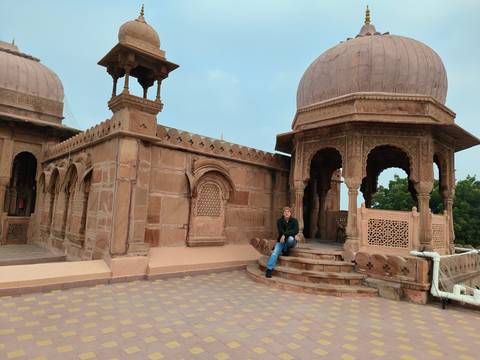       Man sitting in a historical site with domed structures.
  