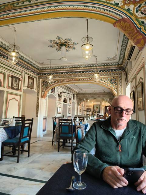       Man sitting in a colorful, intricately decorated restaurant.
  