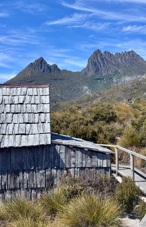 Roof of a wooden cabin with mountains in the background.