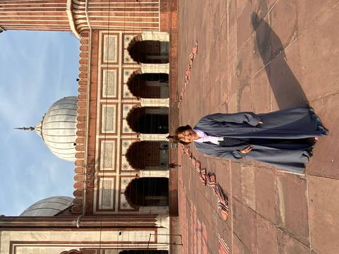 Visitor posing in front of a grand mosque with traditional architecture.