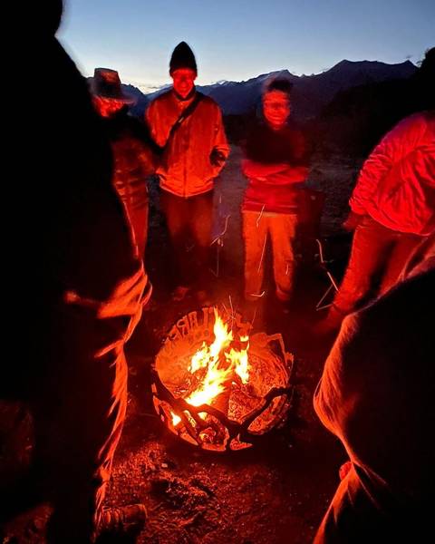       People gathered around a campfire during nighttime.
  