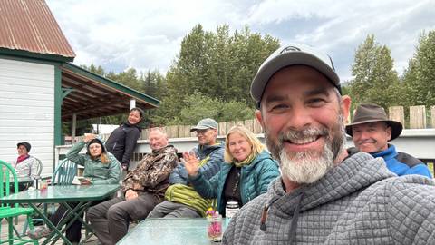       Group of people seated outdoors at a table with smiles.
  