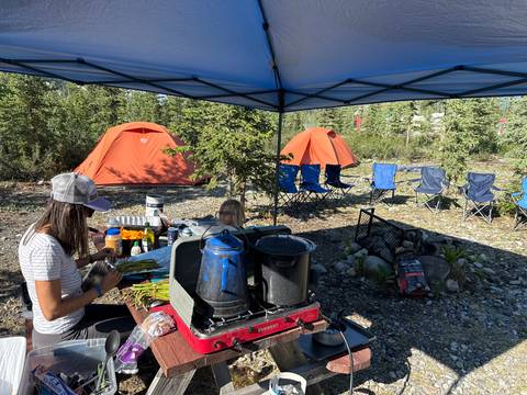       Camp setup with tents, cooking, and dining area.
  