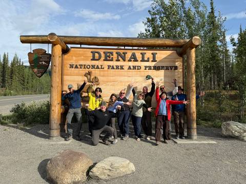       People posing at the entrance of Denali National Park.
  