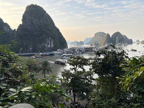       View of ships and boats in a bay surrounded by limestone cliffs.
  