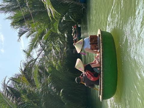       People in a round bamboo boat on a lush river.
  