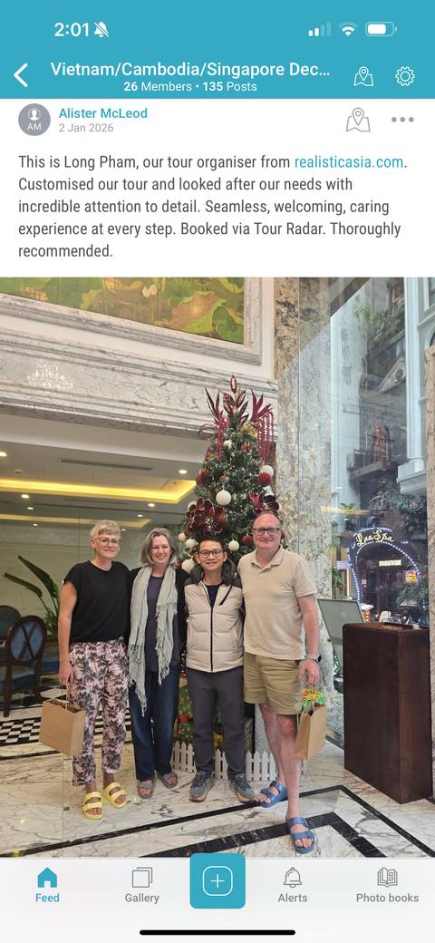       Group of people posing in front of a decorated Christmas tree indoors.
  