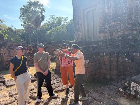       Tourists listening to a guide at ancient ruins.
  