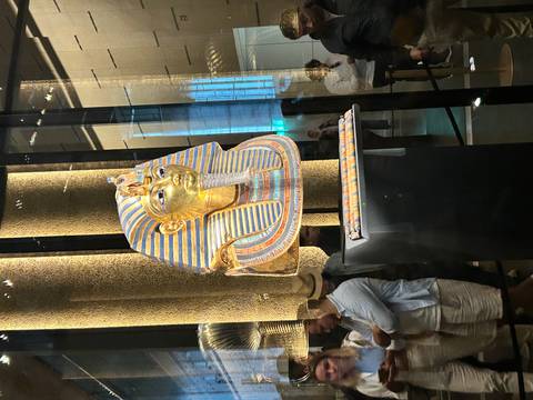      A golden mask of an ancient Egyptian figure on display.
  